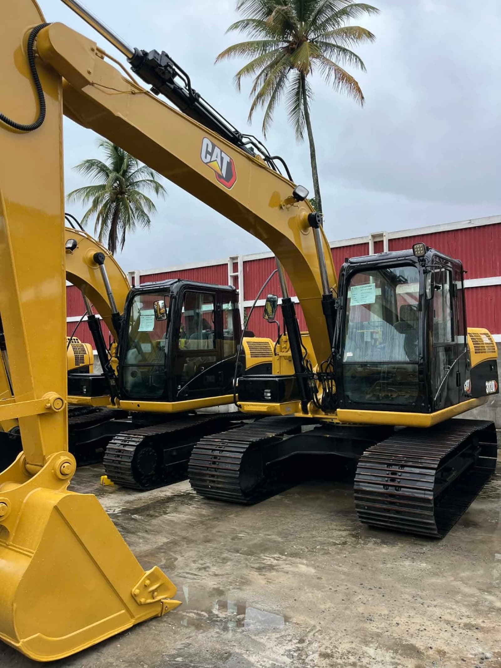 Two Caterpillar 312D tracked excavators staged side by side on a BCLI yard in Guyana.